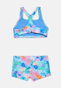 Πολύχρωμο αθλητικό σουτιέν με μπλε βάση και λουλουδάτο μοτίβο υδατογραφίας. Συνοδευτικά σορτς με το ίδιο μοτίβο, κατασκευασμένα από ελαστικό ύφασμα.