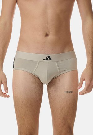 Boxers beiges pour hommes avec un logo Adidas noir sur la ceinture. Fabriqués en tissu doux, ils présentent un design ajusté et des détails de couture minimaux.