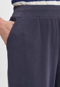 Marineblauwe sportbroek met zijzakken, gemaakt van een zachte, gestructureerde stof met een elastische tailleband en een ontspannen pasvorm.