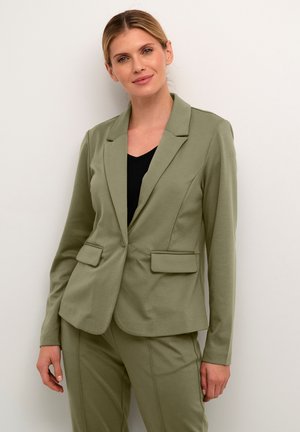 Olivově zelený blazer s přiléhavým střihem, s jedním knoflíkem a dvěma předními kapsami. Tkanina je hladká s mírným elastickým efektem.