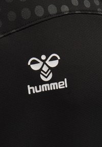 Maglietta sportiva nera con un motivo testurizzato in tonalità più chiare e un logo "hummel" bianco con un design di ape sopra di esso.