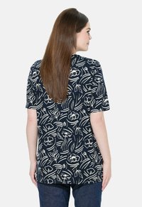 Top corto de manga corta en color navy con patrones botánicos blancos; presenta un corte relajado y un dobladillo curvo. Hecho de una tela suave y ligera.