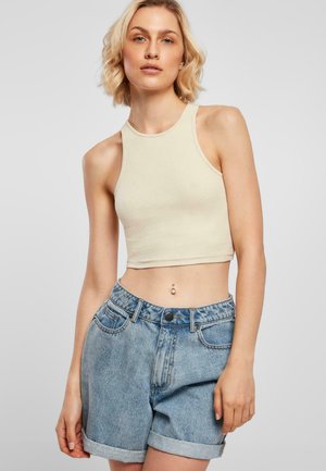 Cremfarbener, gerippter Cropped-Top mit hohem Kragen, kombiniert mit hellblauen Denim-Shorts mit umgeschlagenen Säumen und Fünf-Taschen-Design.