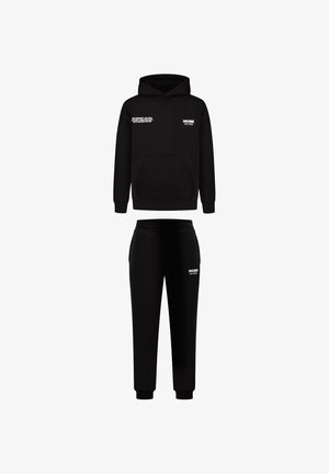 Conjunto de sudadera y pantalones deportivos negros. La sudadera cuenta con un bolsillo frontal y texto blanco. Tela suave, corte relajado, pantalones ajustados con puños elásticos.