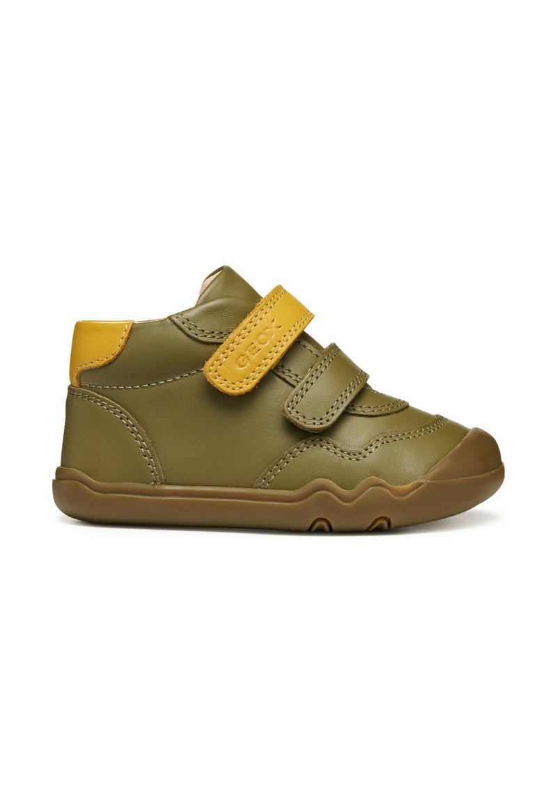Sneaker verde in pelle con dettagli gialli, dotata di una fascia in Velcro, punta arrotondata e suola in gomma testurizzata per una migliore aderenza.