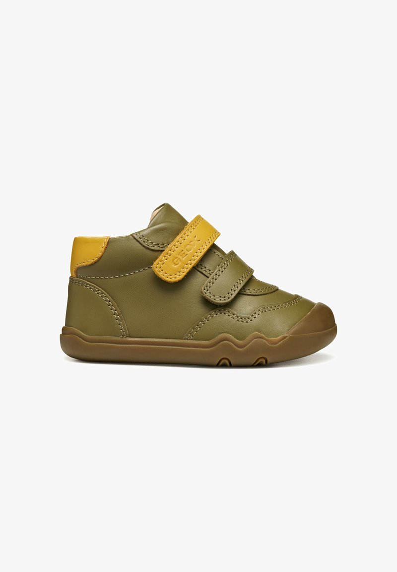 Sneaker verde in pelle con dettagli gialli, dotata di una fascia in Velcro, punta arrotondata e suola in gomma testurizzata per una migliore aderenza.