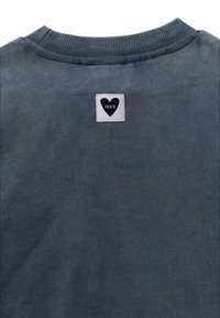 Sudadera gris con una textura suave, cuello de canalé y una pequeña etiqueta de marca en blanco y negro con un logo de corazón en la parte posterior.