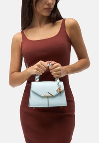 Borsa a tracolla azzurra chiara con design strutturato, dettagli dorati e manico intrecciato. Presenta una chiusura triangolare e una superficie testurizzata.