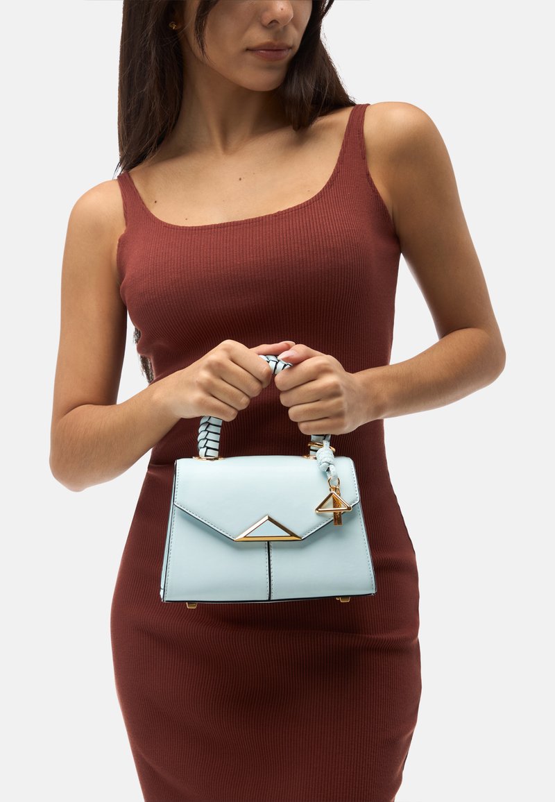 Sac à main bleu clair avec un design structuré, des accents dorés et une poignée tressée. Présente un fermoir triangulaire et un corps texturé.