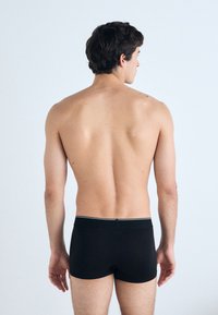 Black boxer shorts with a slim fit, featuring a contrasting white waistband. Smooth texture, designed for comfort and support.