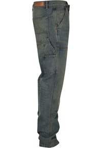 Blue denim work pants with multiple pockets, slightly tapered leg design, and heavy stitching. Dark wash with a worn texture and brown waistband label.