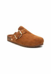 Zapato slip-on de ante marrón con punta redondeada, doble hebilla de acero y suela de corcho texturizada. Presenta un acabado suave y mate.