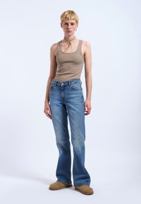 Beige ribbad toppi yhdistettynä vaaleansinisiin leveälahkeisiin farkkuihin, joissa on haalistunut pesu. Asusteina on vaaleanruskea choker ja beige jalkineet.