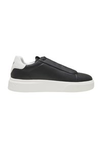 Baskets basses noir et blanc avec une semelle blanche épaisse, une tige noire lisse et un col de talon blanc sur fond blanc.
