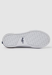 Suola di sneaker bianca in gomma con un motivo a zigzag texturizzato e un logo sul lato. Il tallone presenta una piccola etichetta blu navy.
