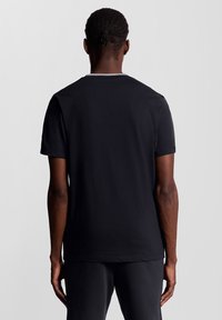 Svart kortärmad t-shirt med rundad halsringning, som visar en slät tygstruktur och minimala sömnadsdetaljer på baksidan.