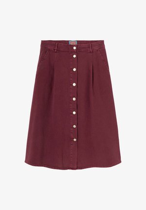 Jupe évasée bordeaux en coton. Elle présente un devant à boutons, deux poches latérales et un ourlet qui se courbe doucement vers le haut sur les côtés.