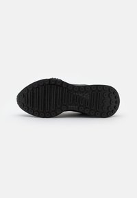 Semelle de chaussure de sport noire avec un motif à relief combinant textures circulaires et côtelées, fabriquée en caoutchouc. Comprend des rainures flexibles pour une meilleure adhérence.