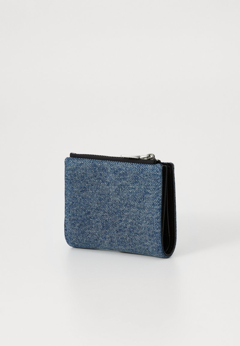 Portafoglio in denim con un esterno blu testurizzato, chiusura a zip e dettagli in pelle nera. Forma rettangolare compatta.