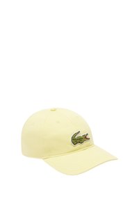 Gorra de algodón amarilla con visera curva, que presenta un logo de cocodrilo bordado en verde y rojo en la parte frontal. Diseño de seis paneles con ojales.