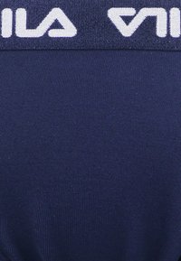 Fascia per sport di colore blu navy con texture a coste e logo "V" bianco prominente, progettata per comfort e flessibilità.