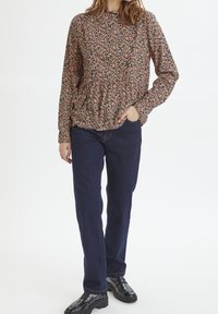 Blommig peplumblus i mörkrosa, med svarta detaljer och långa ärmar. Matchas med mörkblå jeans och svarta platåskor.