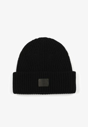 Black knitted beanie with a ribbed texture, featuring a folded cuff and a small rectangular leather logo patch on the front.