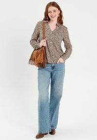 Leopardenmuster Hemd mit langen Ärmeln, kombiniert mit hellblauen weiten Jeans und einer braunen Fransenhandtasche. Braune Ankle Boots.