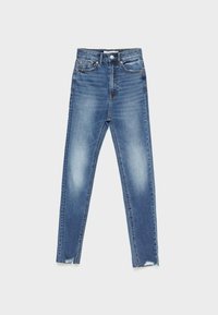 Jean skinny taille haute en denim bleu moyen avec décoloration, ourlets effilochés et style classique à cinq poches. Texture lisse.