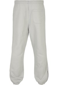 Hellgraue Sweatpants mit einem elastischen Bündchen, schmal zulaufenden Beinen und einer einzelnen Gesäßtasche. Glattes Material mit dezenten Nähdetails.