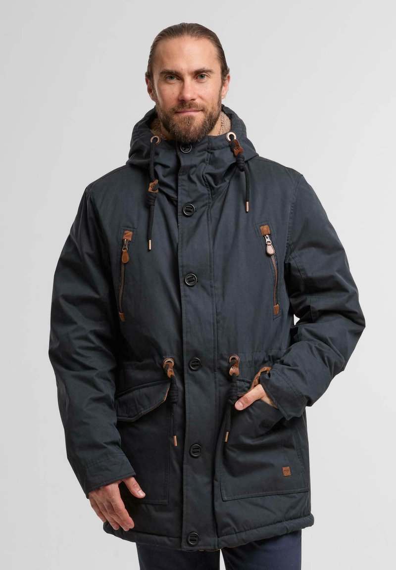 Parka noire avec capuche à cordon de serrage, fermetures éclair et boutons, accents beige, deux poches avant et doublure intérieure chaude.