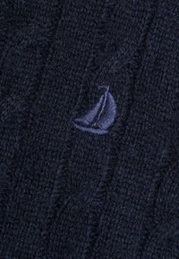 Pulover tricotat navy cu model în cablu și textură moale; prezintă un mic logo brodat cu o bărcuță în nuanțe de albastru închis.