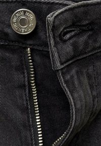 Črn denim material z vgraviranim srebrnim zadrgo, kovinsko gumbasto zapiranje in všitimi robovi, ki poudarjajo teksturirano površino in čiste linije.
