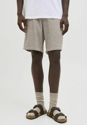 Shorts en velours côtelé beige avec des rayures horizontales, coupe décontractée. Assortis avec des chaussettes grises claires et des sandales brunes à une seule sangle à boucle.