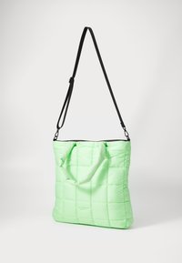 Quilted tote bag in light green, featuring dual handles and an adjustable black shoulder strap. Smooth texture with a simplistic design.