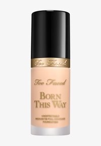 Too Faced Born This Way foundation in een matglazen fles. Zwarte dop, gouden accenten en beige vloeistof zichtbaar aan de binnenkant.
