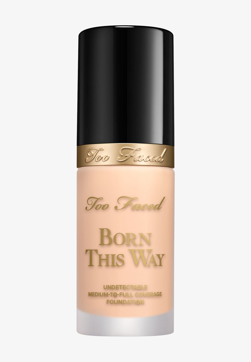 Too Faced Born This Way foundation in een matglazen fles. Zwarte dop, gouden accenten en beige vloeistof zichtbaar aan de binnenkant.