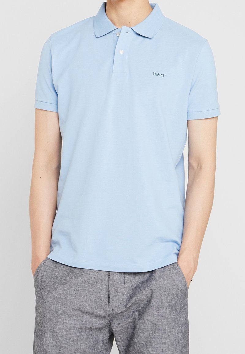 Polo bleu ciel en coton doux avec un col classique, des manches courtes et un petit logo brodé sur la poitrine gauche.