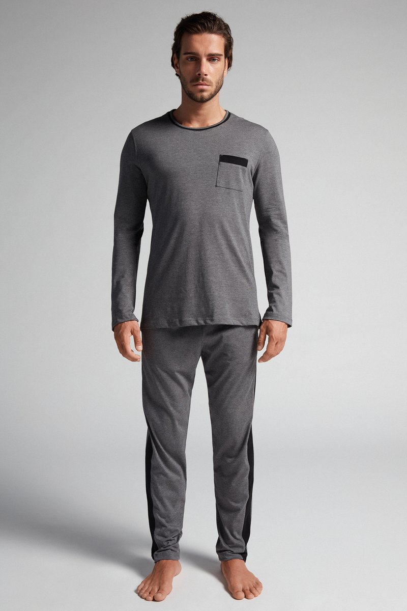 Grijze langslieve shirt met een zwarte zak en bijpassende broek met zwarte zijstrepen. Zachte stof met een relaxte pasvorm.