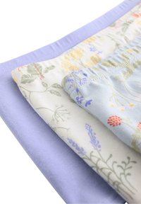 Tre stoflag: det øverste i ensfarvet lyslilla, det mellemliggende med et blomsterpattern i pastelfarver, og det nederste i blødt hvidt med grønne blomsteraccenter.