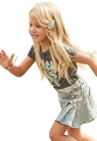 Ragazza che indossa una maglietta grigia con una grafica e una gonna di jeans chiara. La gonna presenta pieghe e tasche. Capelli lunghi e mossi di colore biondo.