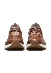 Sneaker in pelle marrone con tomaie testurizzate, chiusura con lacci e una suola in gomma bianca con un motivo ondulato. Logo sulla linguetta del tallone.