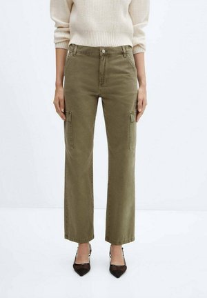 Woman wearing olive green straight-leg cargo pants, cream knit sweater, and black pointed-toe heels, standing against a white background.