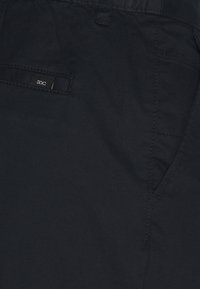 Pantaloni EDC di colore blu navy scuro realizzati in tessuto misto cotone. Tra le caratteristiche troviamo una tasca frontale, dettagli di cucitura e un'etichetta tessuta sul retro.