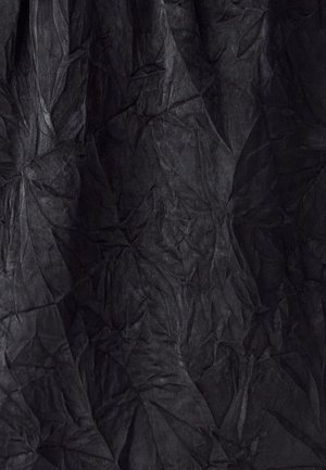 Sadrumots melns audums ar teksturētu virsmu, izceļot izteiktas krokas un saliekumus, radot dinamisku un slāņainu izskatu.