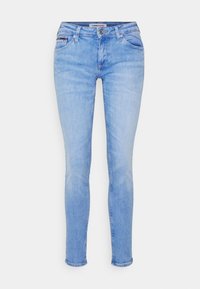 Jeans de denim azul claro con un corte ajustado, cinco bolsillos y cierre de botón. Presentan un leve desgaste y un parche con el logo en la parte trasera.