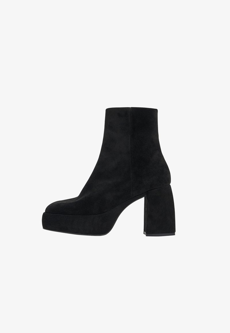 Botas de tobillo de ante negro con un tacón rectangular y chunky, y una suela de plataforma. Textura suave y diseño simple y elegante.
