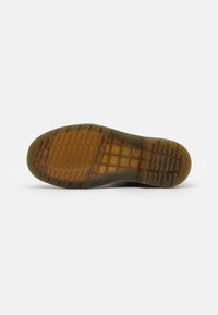 Suela de zapato de goma marrón translúcida con un patrón de textura que presenta ranuras horizontales y verticales sobre fondo blanco.