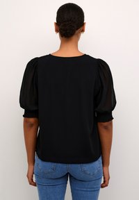 Zwarte blouse met pofmouwen gemaakt van doorzichtig materiaal en elastische manchetten. Gladde stof met een ronde halslijn en een relaxte pasvorm.