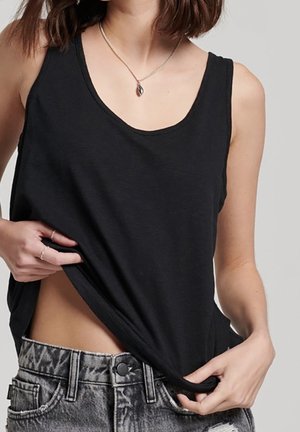 Black sleeveless tank top made of soft fabric, featuring a scoop neckline. Paired with high-waisted distressed denim shorts.